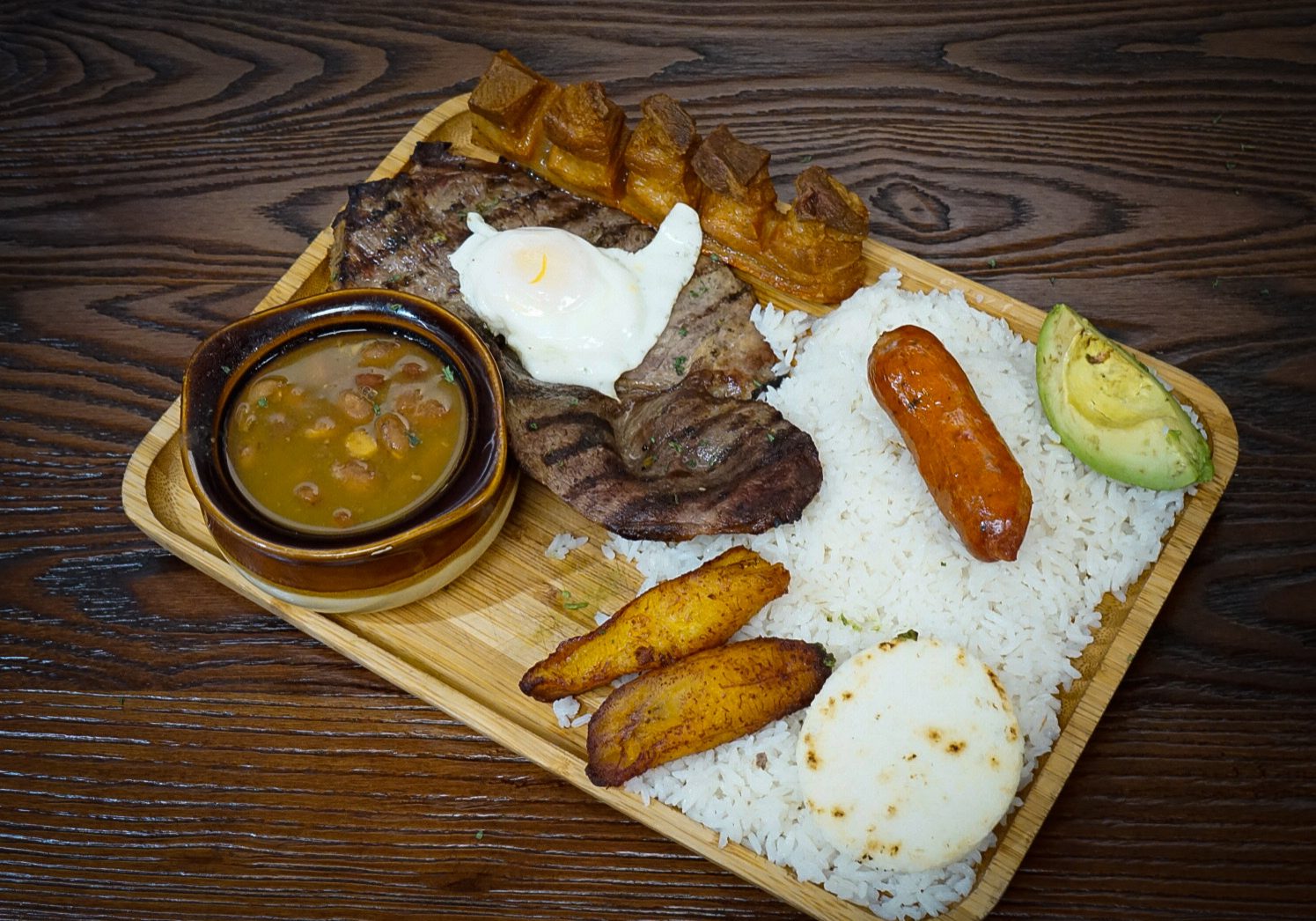 Bandeja Paisa on top of a wooden tablet.